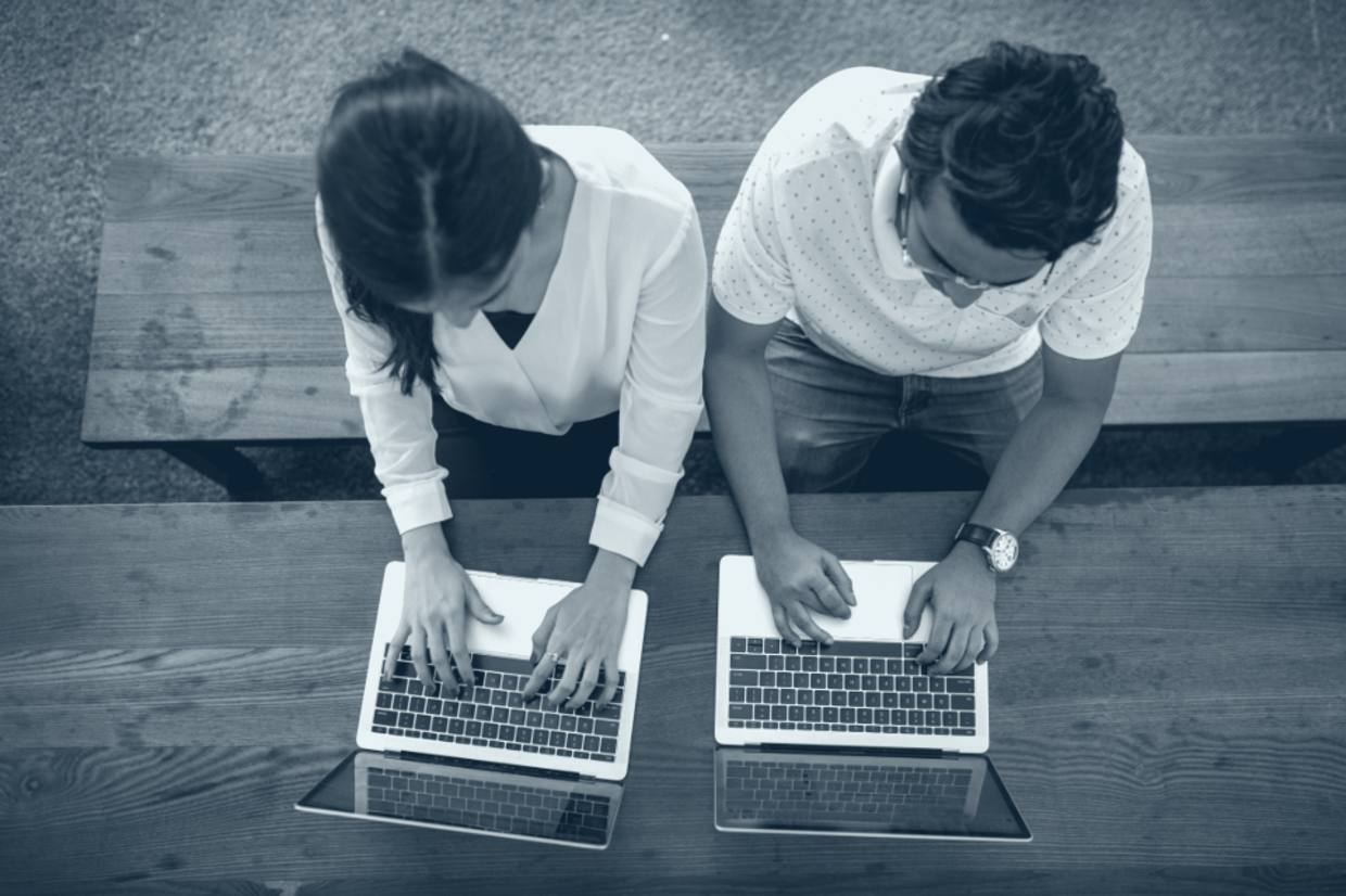 Two professionals collaborating over laptops, viewed from above